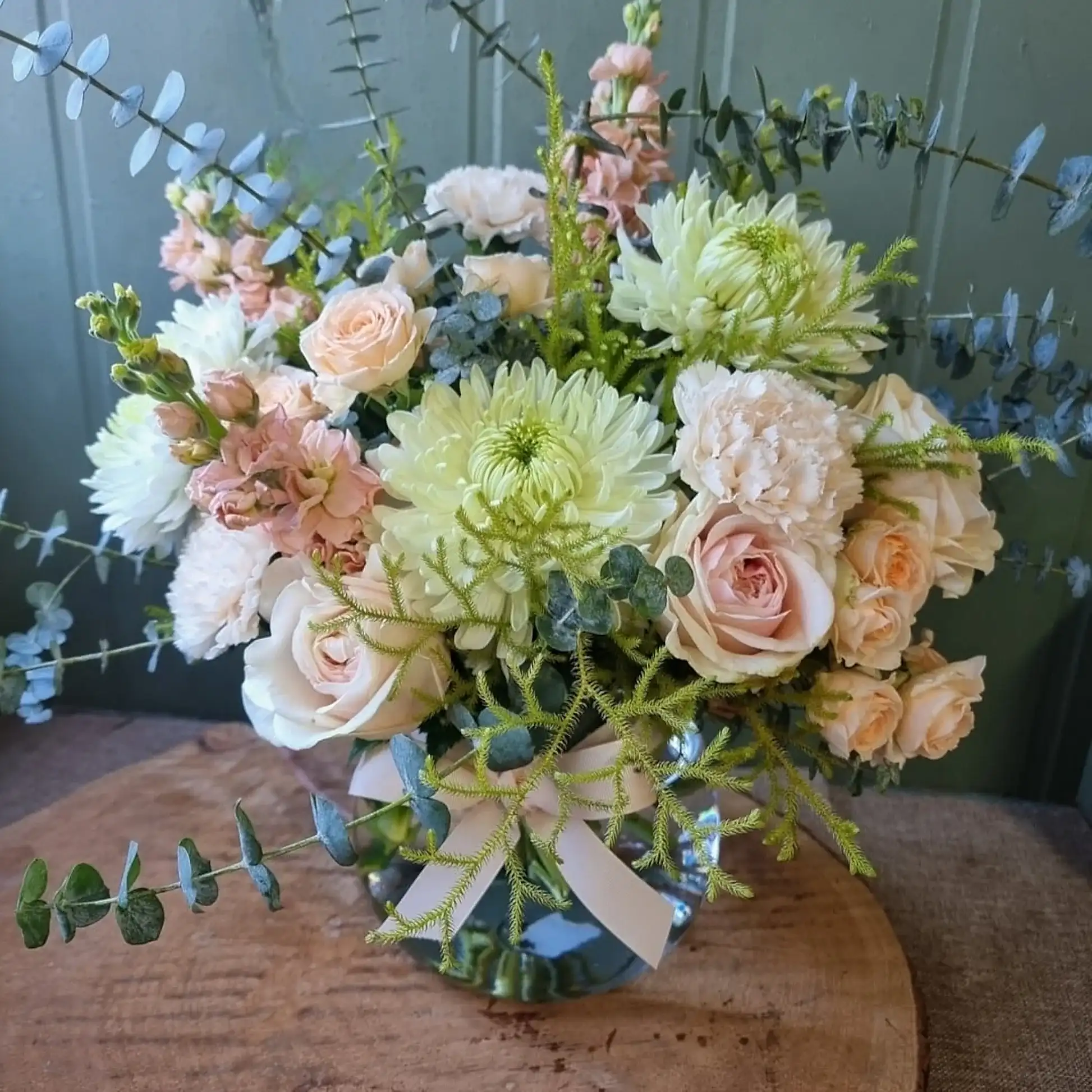 Peach and sage flowers in a fishbowl vase