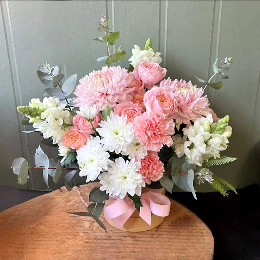 Pink and white tonal flowers arranged in a hatbox